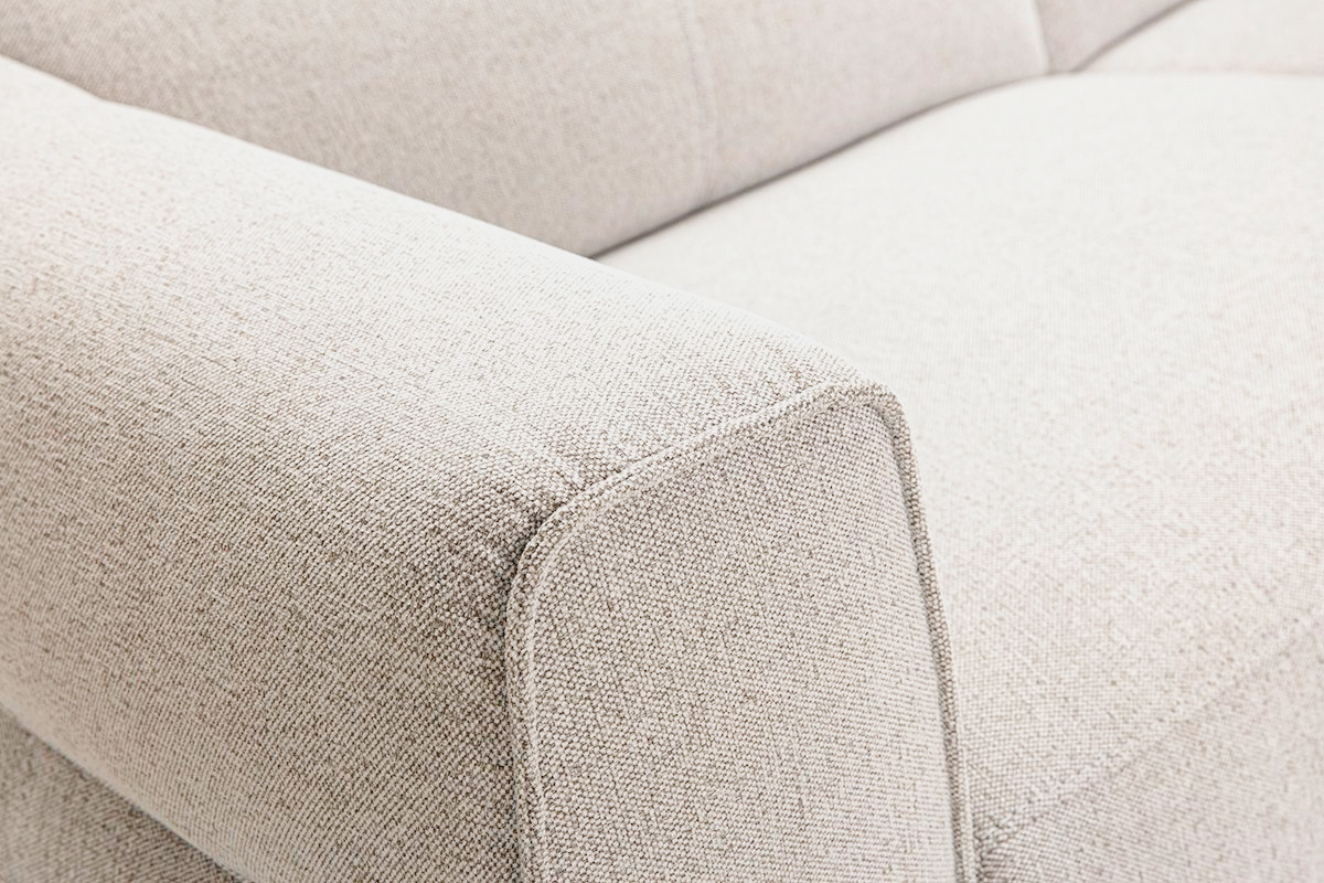 D�tail du canap� 3 places en tissu beige, mettant en avant le t�ti�re et l'accoudoir carr�.