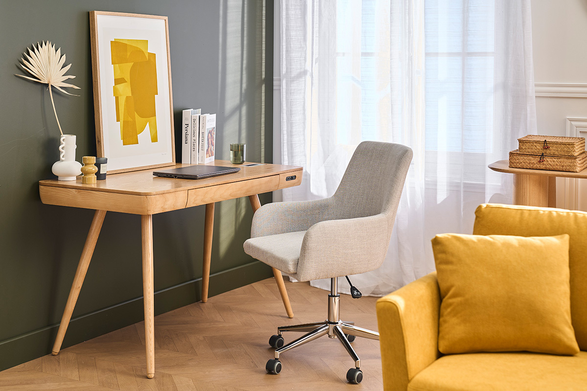 Chaise de bureau en tissu gris clairs SHANA devant un bureau en bois, � c�t� d'un canap� jaune.