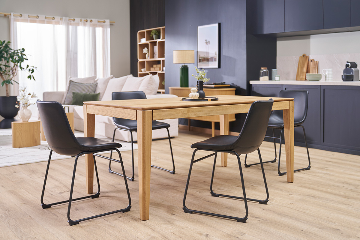 Quatre chaises industrielles noires autour d'une table en bois dans un salon moderne.