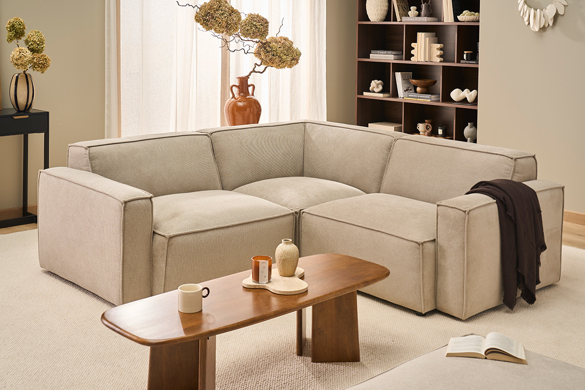 Canap� modulable en tissu chenille beige avec table basse en bois et accessoires d�coratifs, vue d'ensemble.