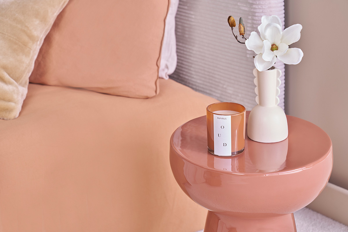 Table d'appoint MOGOU terracotta avec bougie et vase pr�s d'un lit.