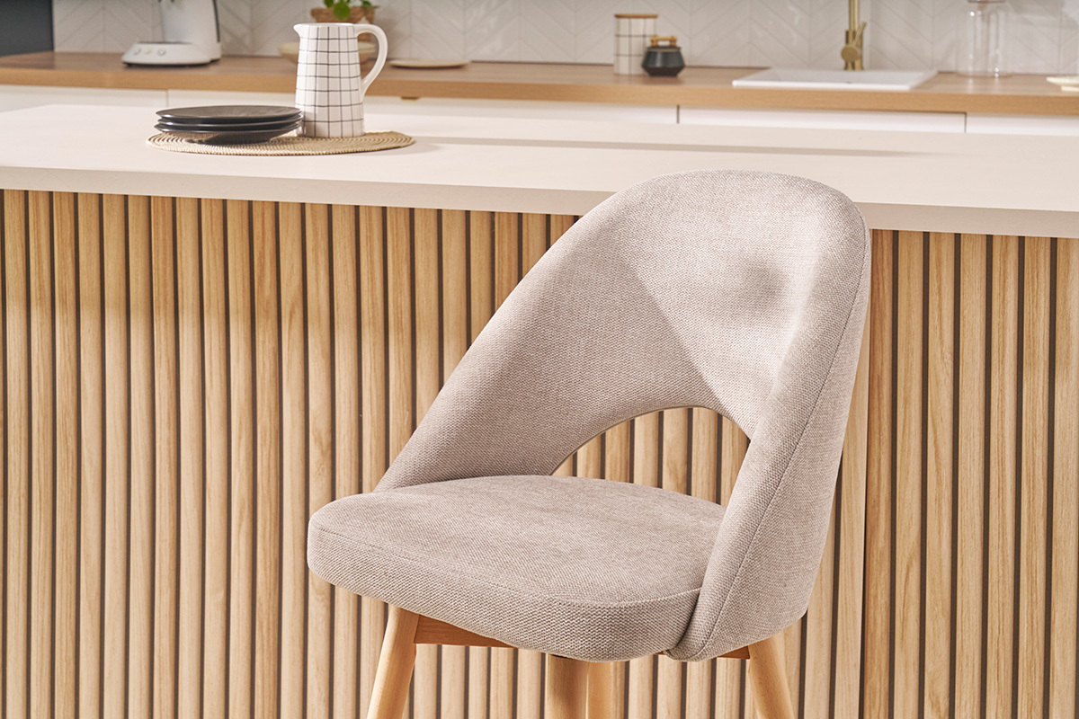 Tabouret de bar scandinave en tissu beige et h�v�a massif devant un comptoir en bois.